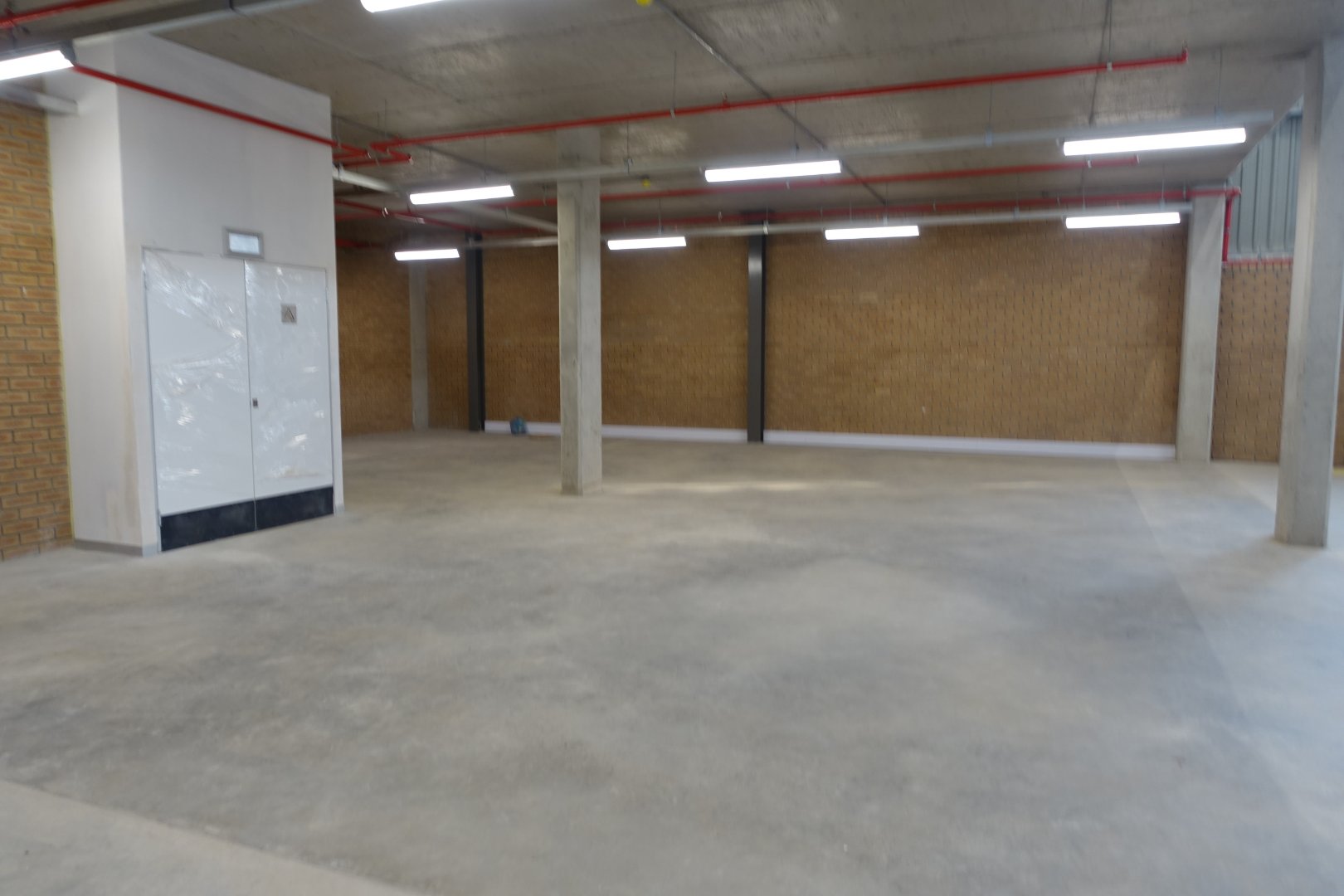 Spacious, empty warehouse with concrete floors and brick walls, suitable for storage or industrial use in Airport Park.