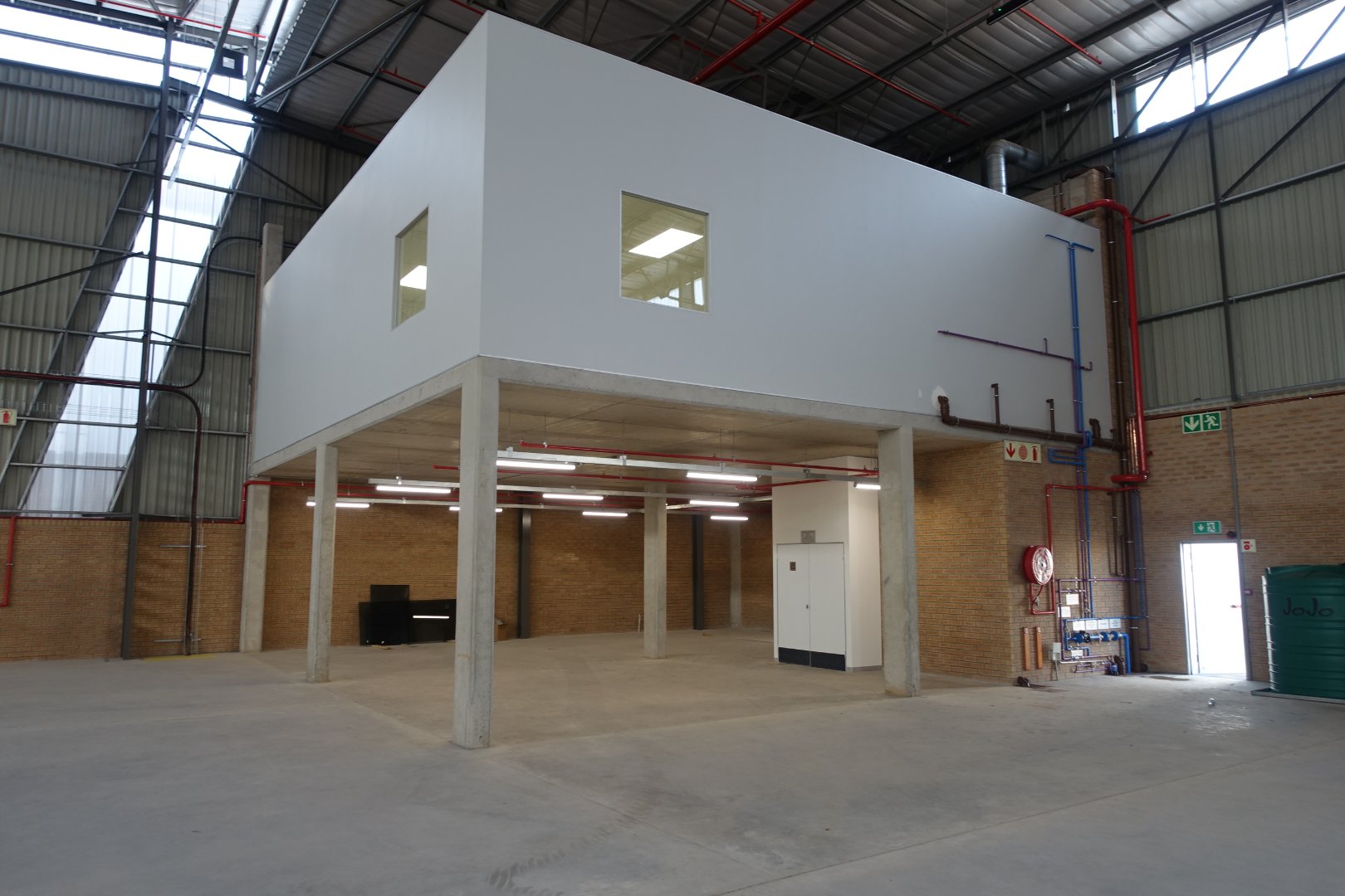 Interior view of a modern warehouse with an upper-level office area, large open space, and high ceilings, suitable for industrial or commercial use.