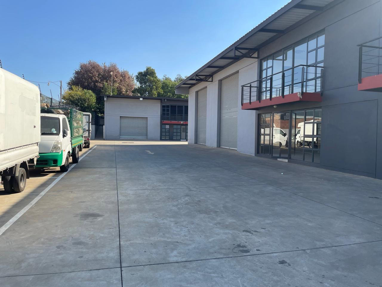 An exterior view of Currie Group's modern offices and warehouses, showcasing a spacious concrete yard, large glass windows, and a clean, professional industrial environment.