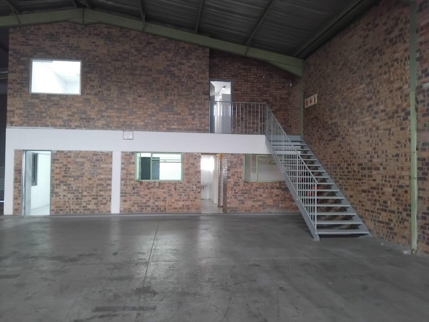 Currie Group Office and Warehouse Interior Modern office and warehouse interior with brick walls, concrete floor, and metal staircase, showcasing the company's industrial facilities since 1887.