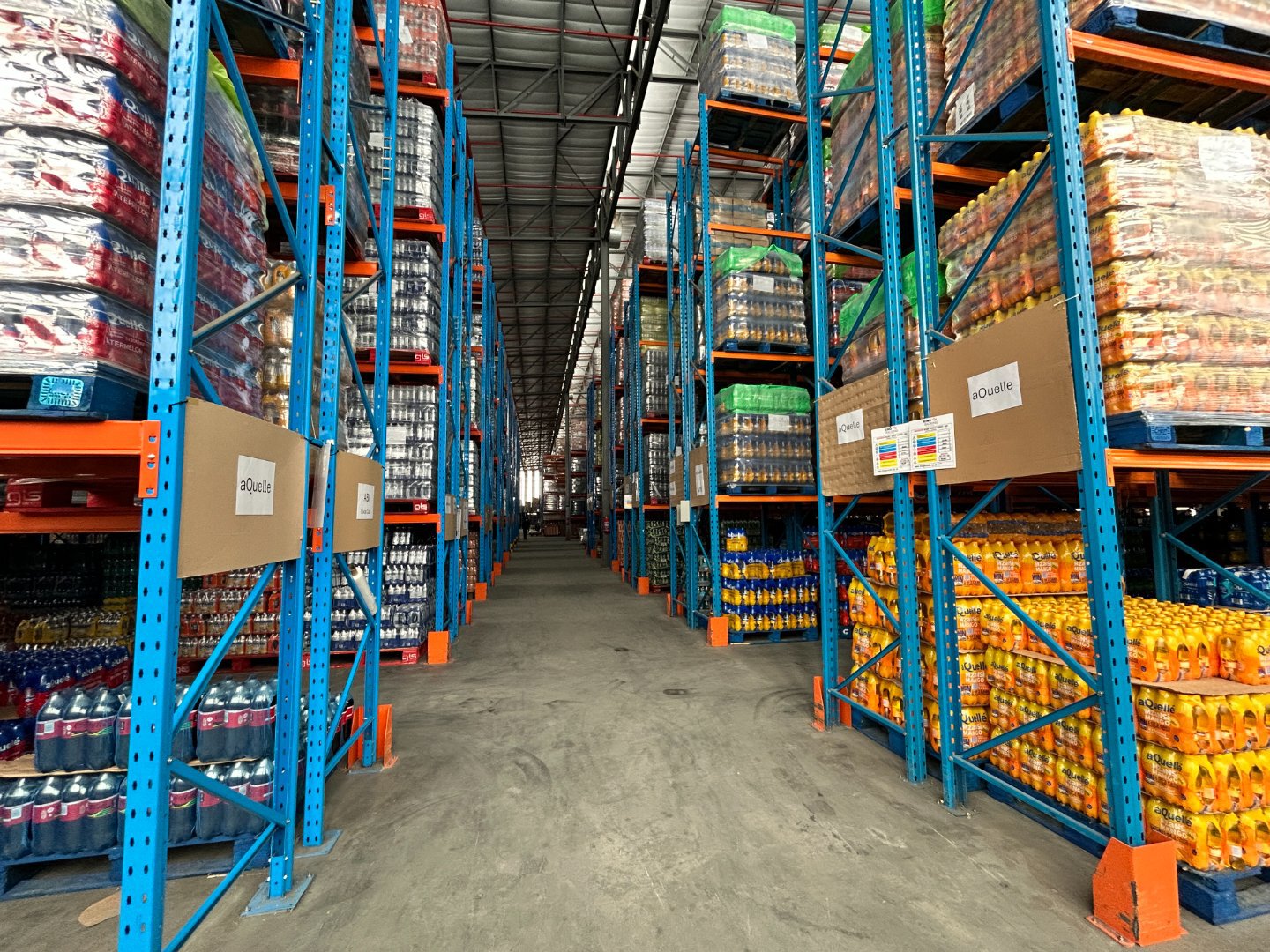 Warehouse shelving with stocked pallets of beverages and supplies. Warehouse shelving with stocked pallets of beverages and supplies.