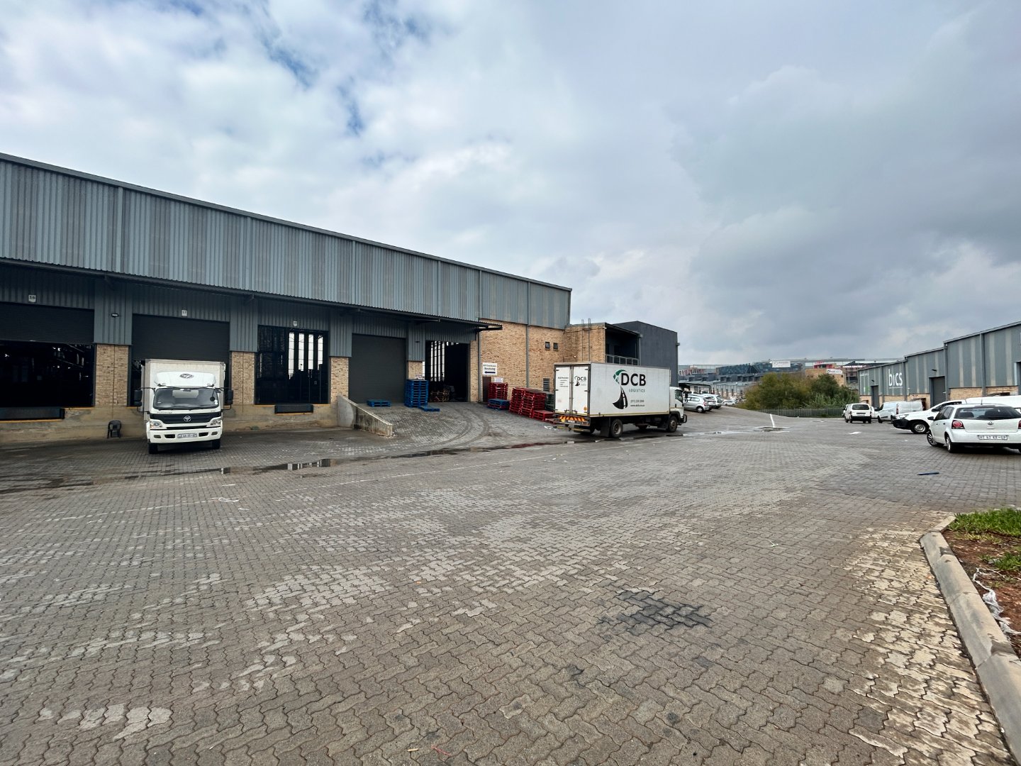 Industrial Warehouse and Office Facility at Currie Group Campus Modern industrial warehouse and office complex with loading docks, trucks, and parking area at Currie Group since 1887.