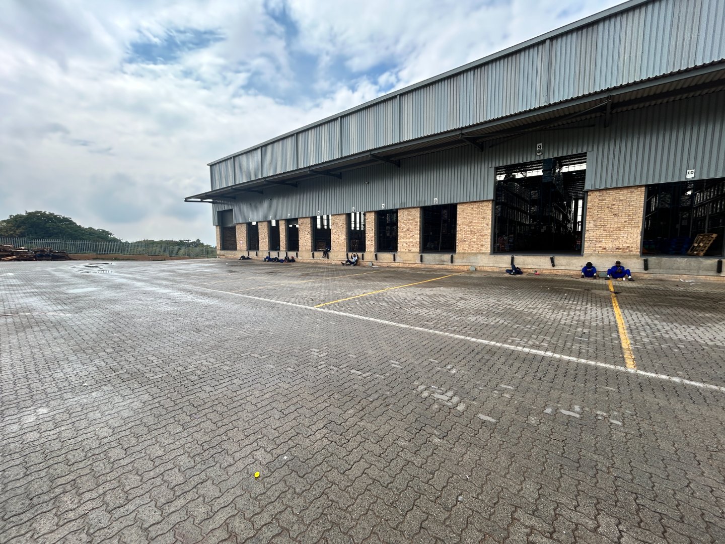 Currie Group Offices and Warehouses Modern industrial offices and warehouses of Currie Group with spacious parking area, brick and metal construction, under a partly cloudy sky.