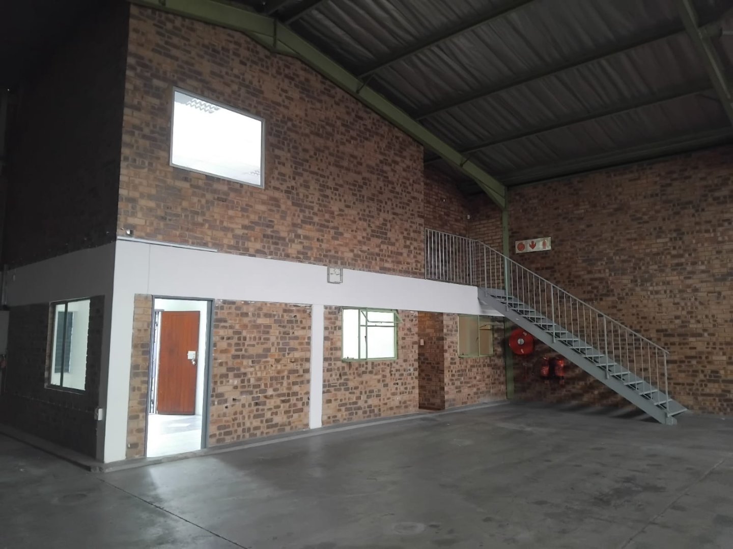 Modern office and warehouse interior with brick walls, metal staircase, and concrete flooring at Currie Group facilities.