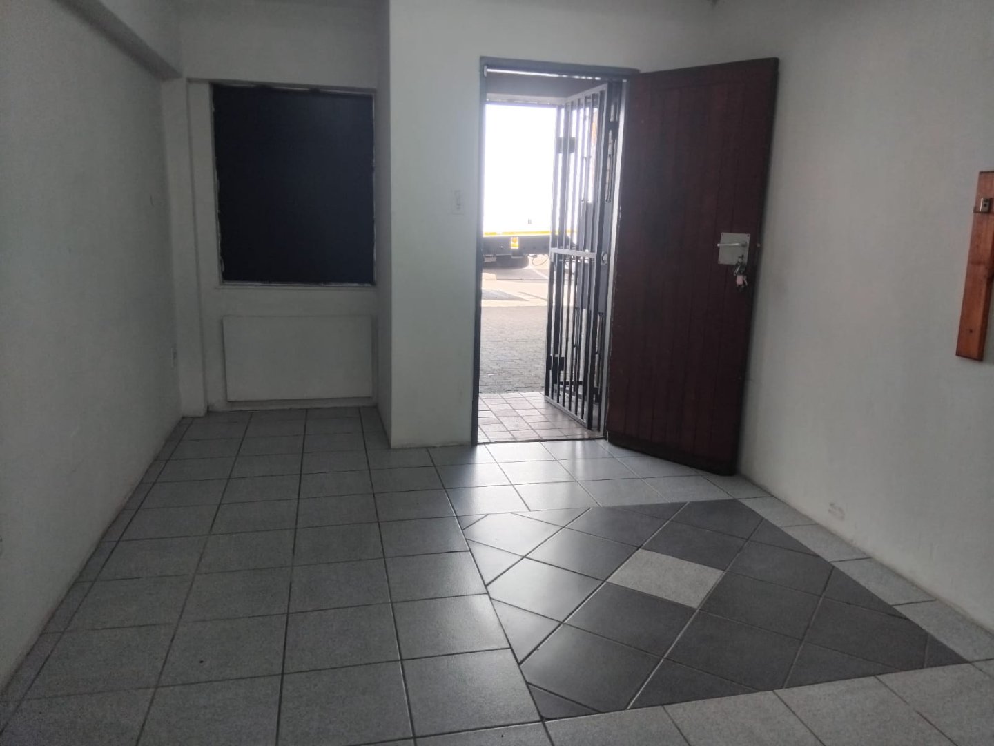 Office entrance with tiled floor, open door, and window, providing access to the warehouse or outdoor area.