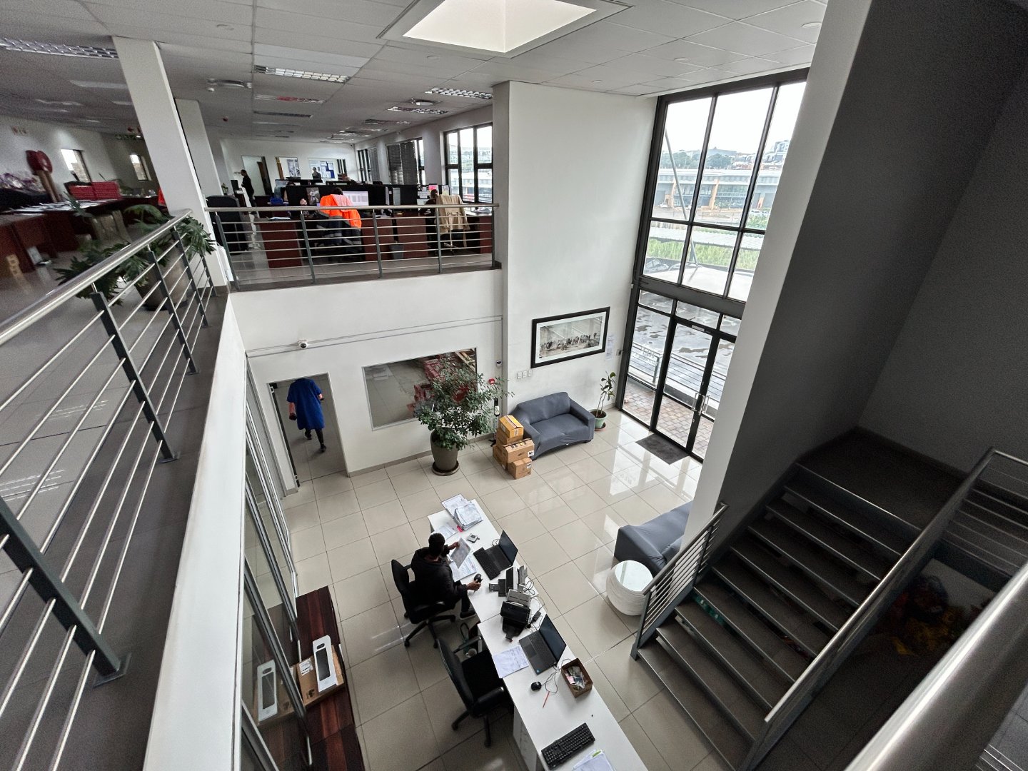 Modern office interior with large windows and open workspace Spacious office area featuring large windows that allow natural light to fill the space, with desks, chairs, and a meeting area, showcasing a professional and welcoming environment.