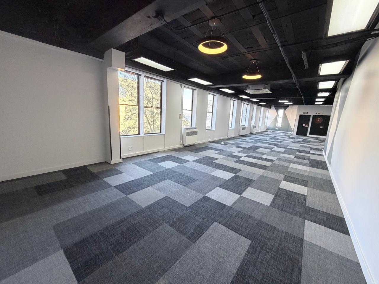 Modern office interior with large windows and stylish ceiling lighting Office space with large windows, contemporary ceiling lights, and a spacious layout suitable for various business needs.