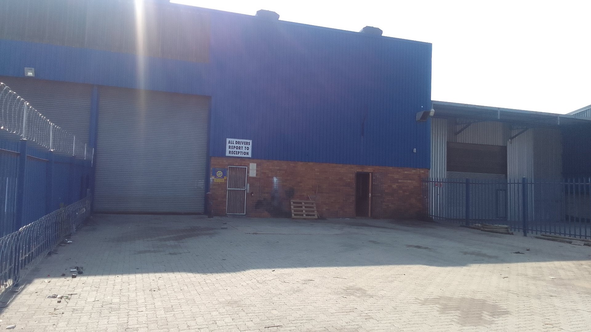 Exterior view of Currie Group offices and warehouses with blue building and paved yard, showcasing industrial facilities since 1887.