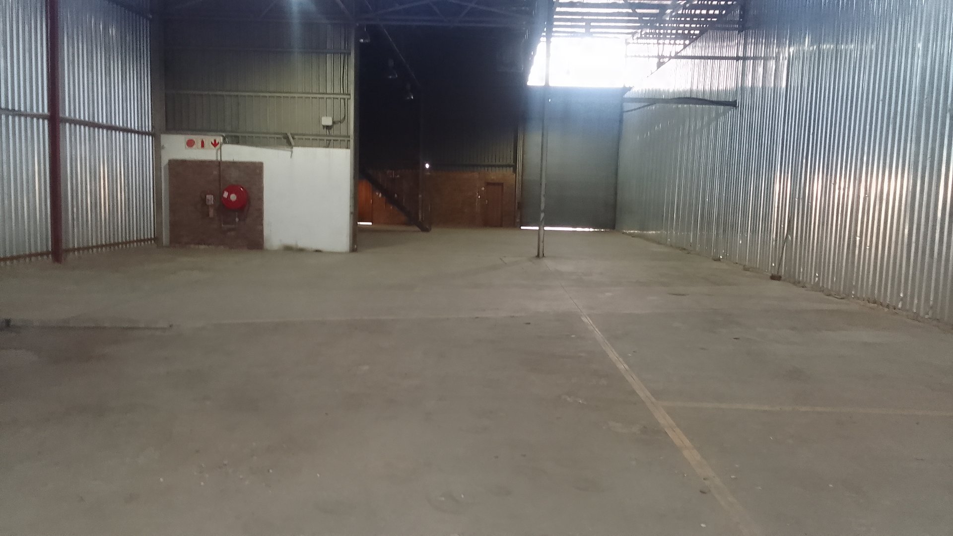 Spacious Warehouse Interior Empty warehouse with metal walls and concrete floor, suitable for storage or industrial use.