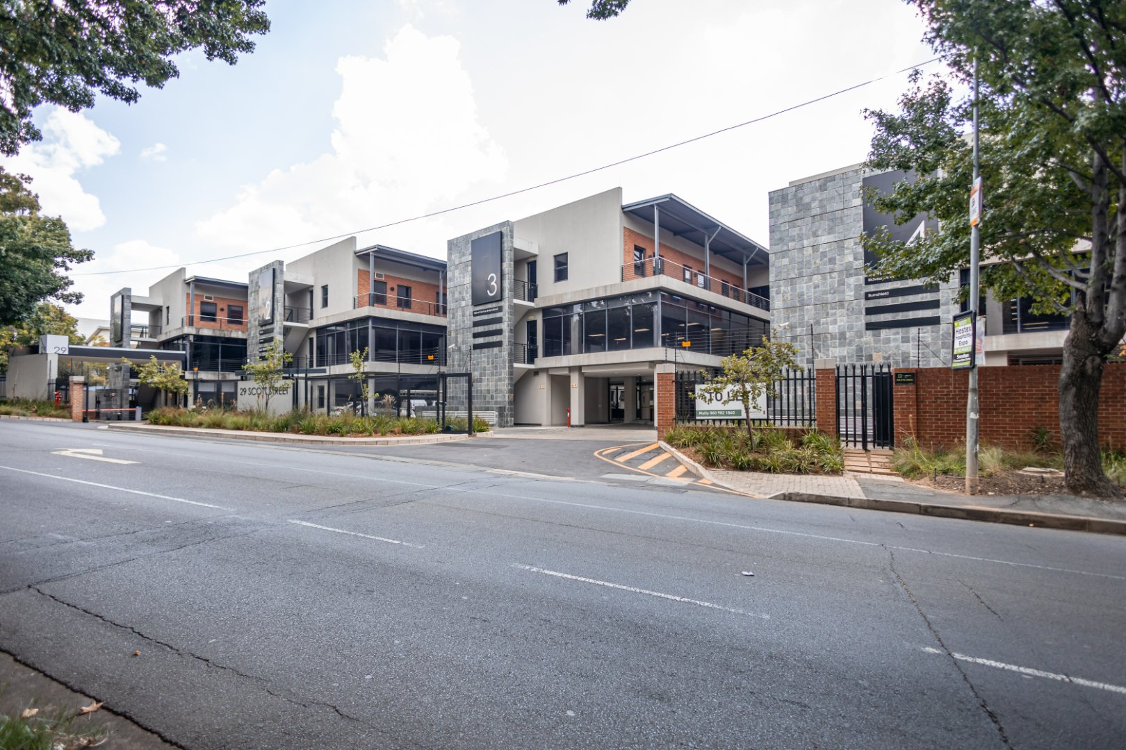 Contemporary office and warehouse buildings with modern architecture, large windows, and surrounding greenery, located in an urban area.