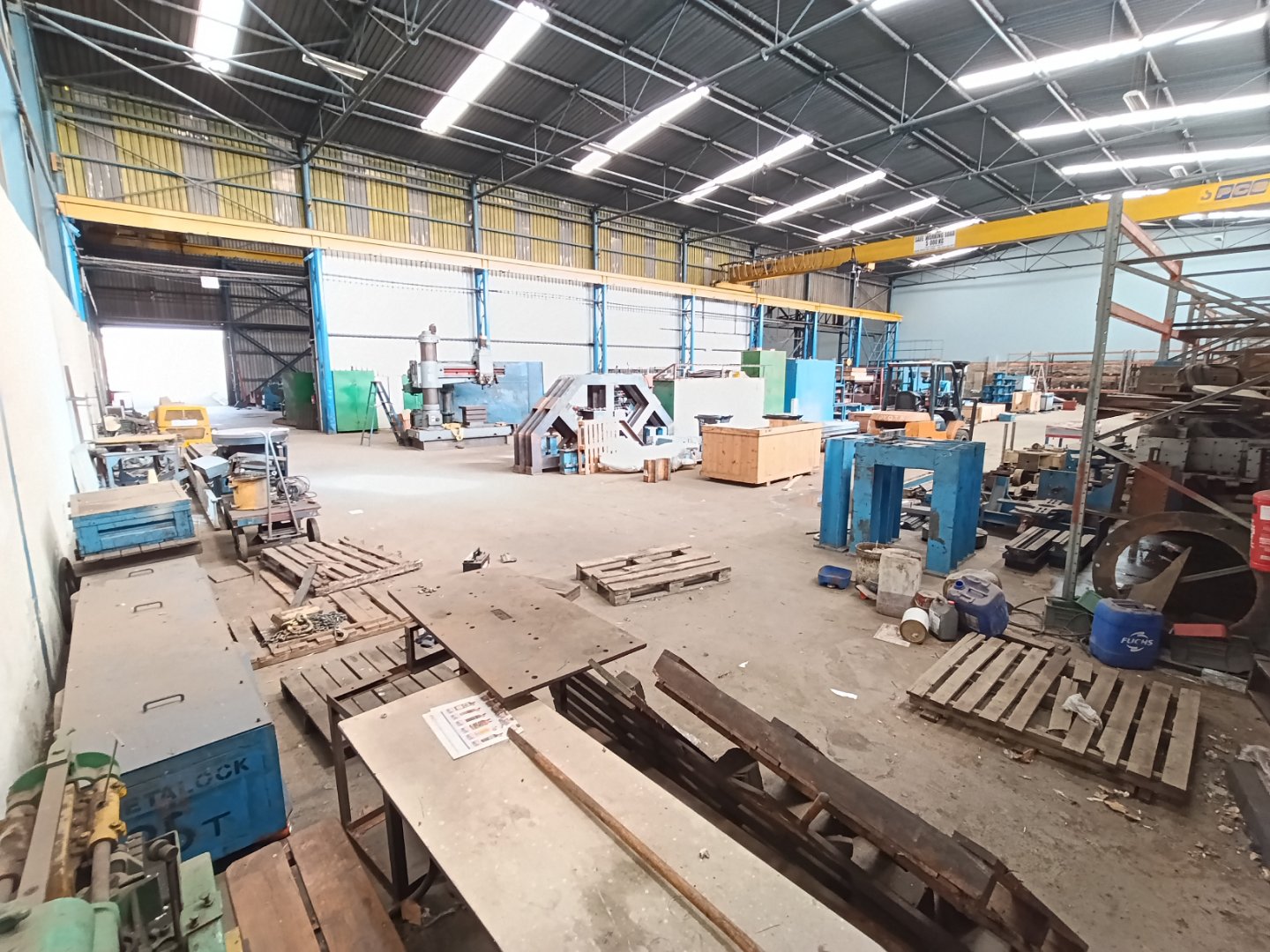 Industrial Warehouse at Currie Group Spacious industrial warehouse with machinery, pallets, and storage racks, showcasing Currie Group's facilities for manufacturing and warehousing since 1887.