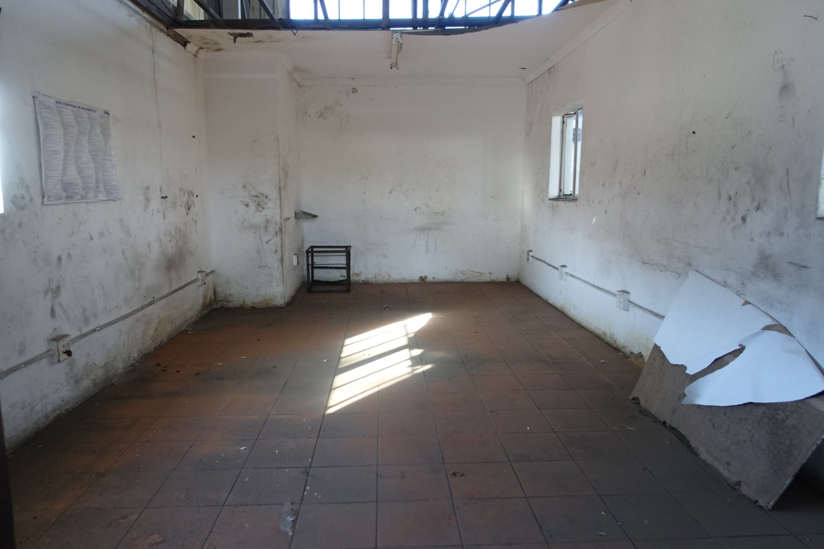 Empty Warehouse Space at Currie Group Spacious, empty warehouse with white walls, tiled floor, and small windows providing natural light, part of Currie Group's office and warehouse facilities.
