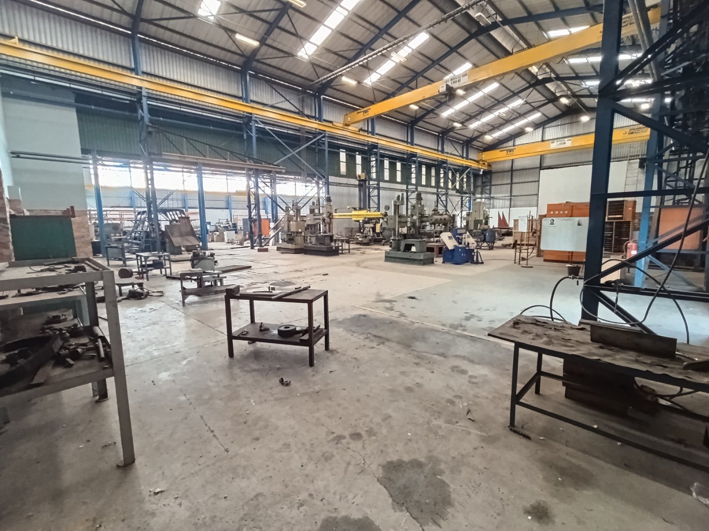 Currie Group Warehouse Facility Spacious industrial warehouse with machinery, workbenches, and overhead cranes, showcasing Currie Group's manufacturing and warehousing capabilities since 1887.