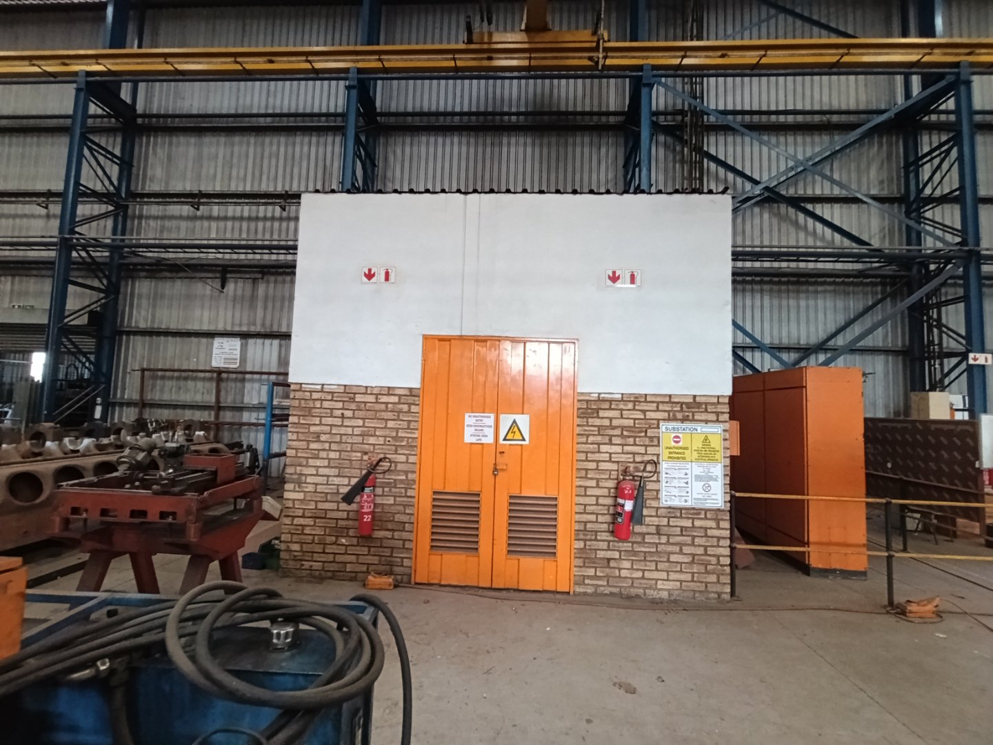 Industrial Storage Facility at Currie Group Inside view of a warehouse with an orange door, brick wall, and storage racks, showcasing industrial storage solutions at Currie Group offices and warehouses.