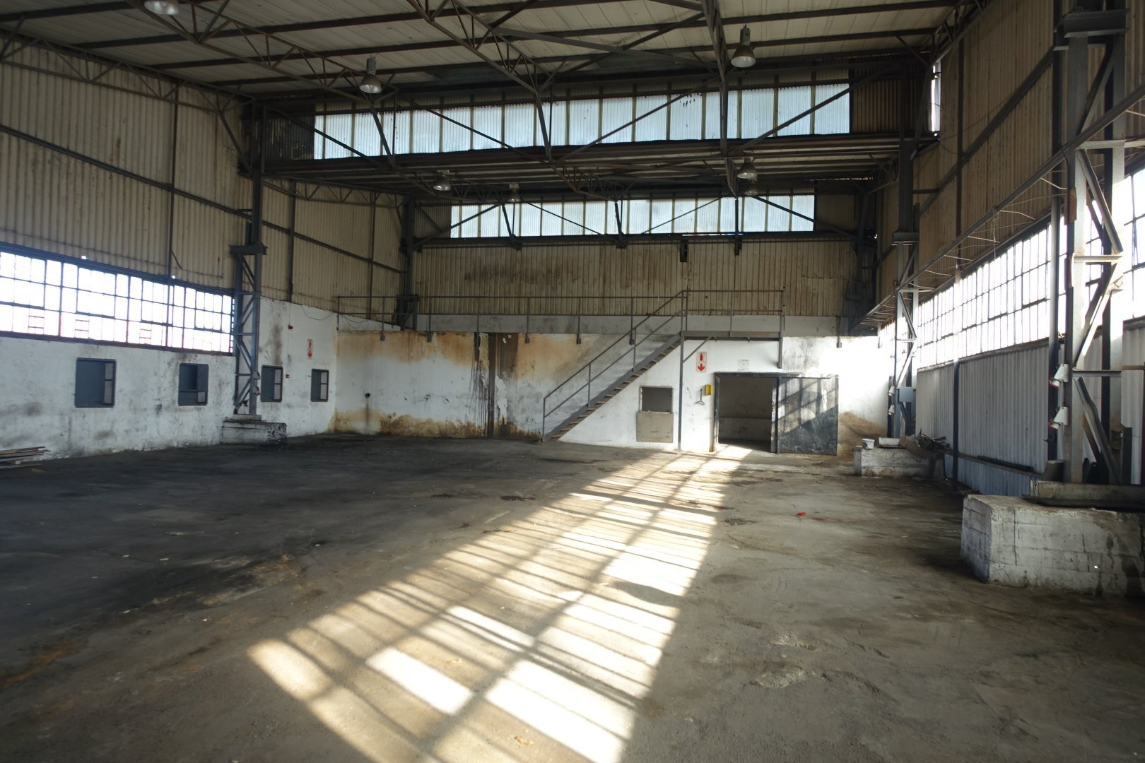 Currie Group Warehouse Interior Spacious industrial warehouse interior with high ceilings, large windows, and concrete flooring, suitable for offices and storage since 1887.