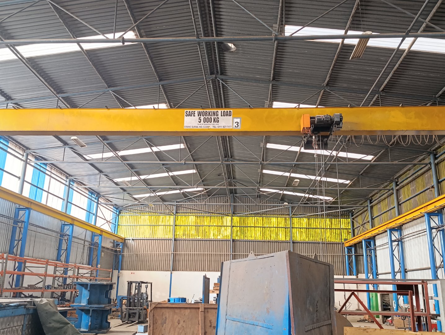 Industrial Warehouse with Overhead Crane Spacious industrial warehouse featuring a yellow overhead crane, high ceilings, and large storage areas, suitable for manufacturing or logistics operations.