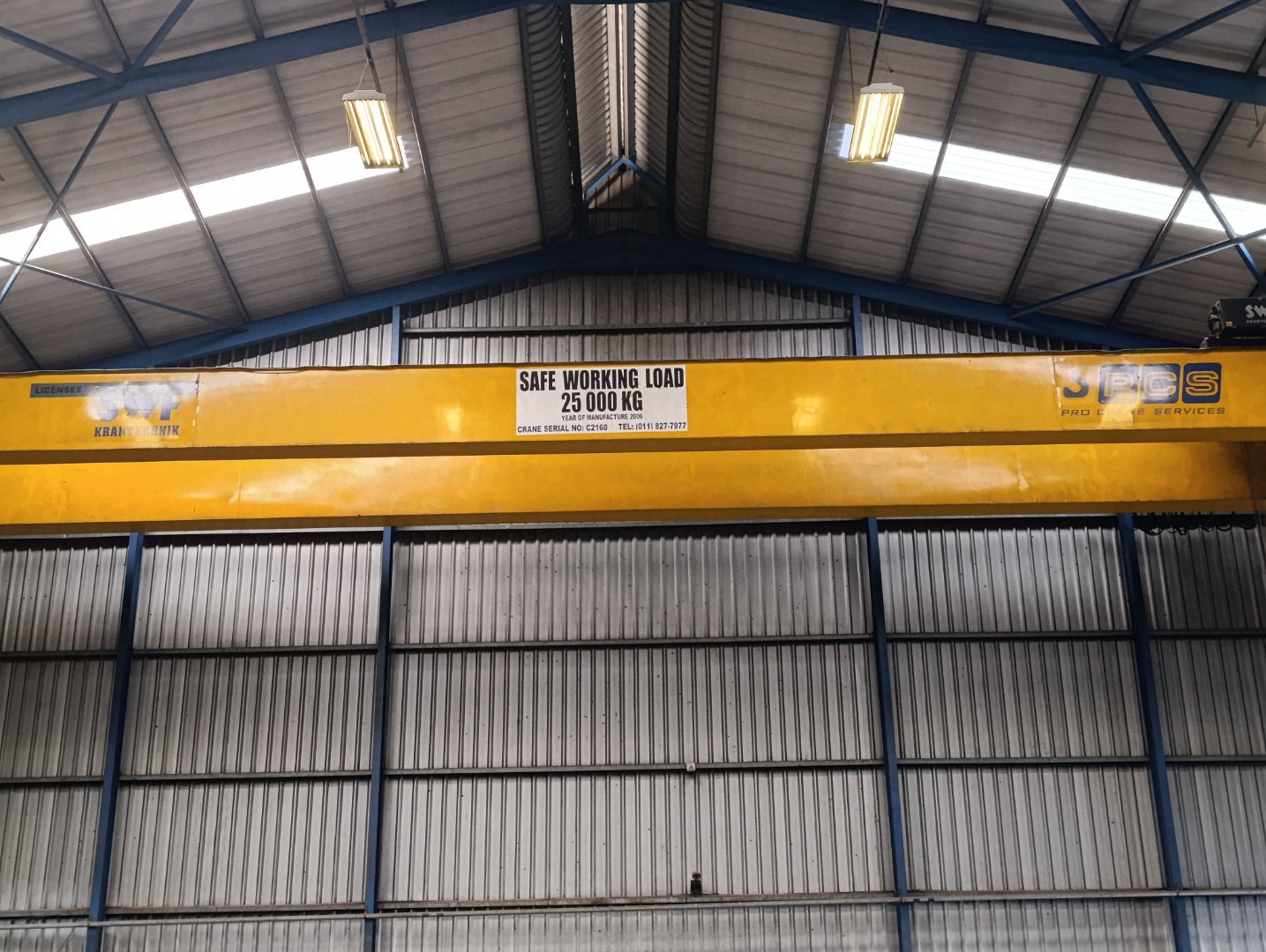 Industrial Crane in Warehouse Yellow industrial crane with safe working load of 25,000 kg inside a warehouse, part of Currie Group's industrial equipment offerings.