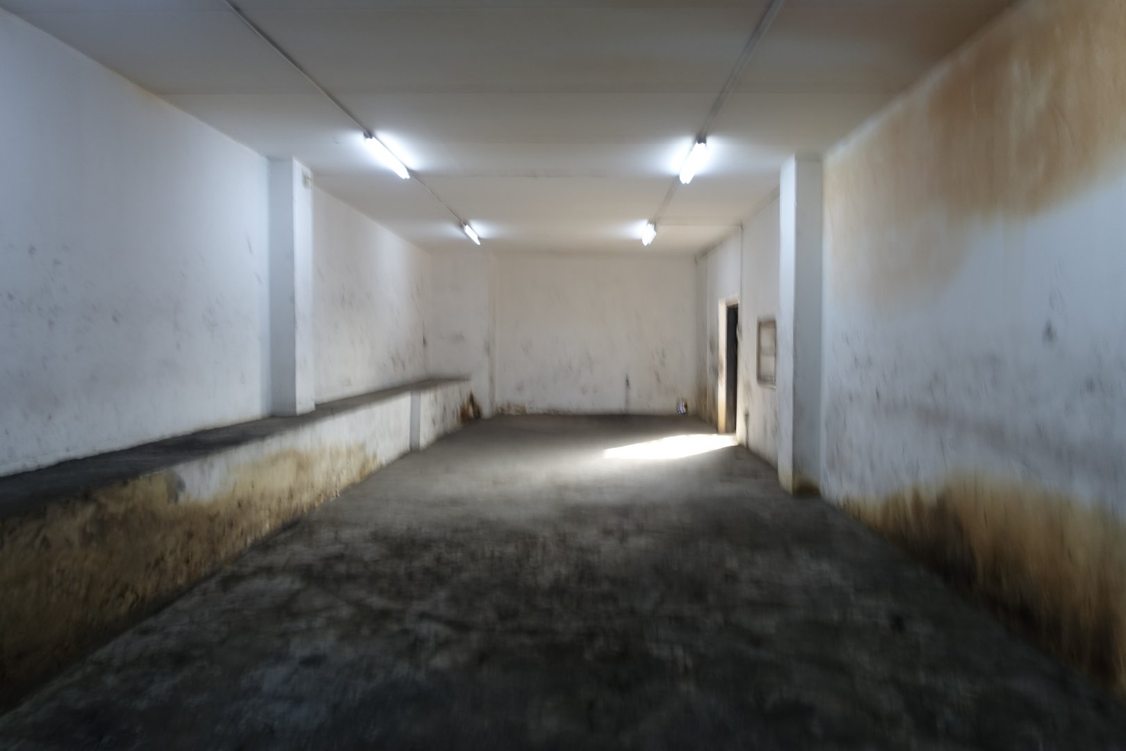 Old Warehouse Interior at Currie Group Interior view of an old warehouse at Currie Group showing worn walls and concrete floor, with minimal lighting and a spacious, industrial atmosphere.