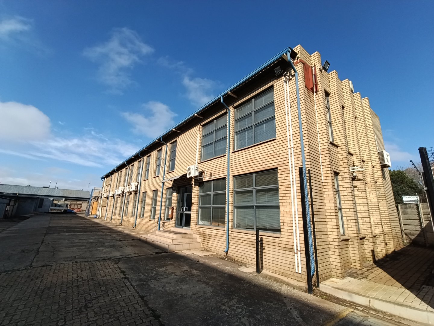 Exterior view of Currie Group offices and warehouses showcasing brick building with large windows under a blue sky.