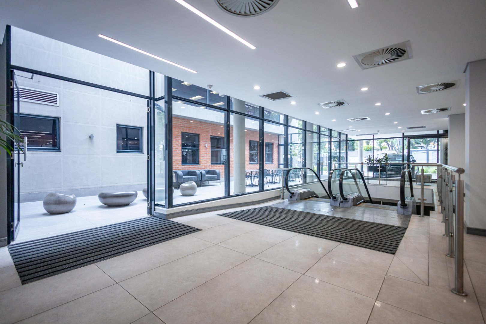 Spacious office entrance featuring large glass walls, modern lighting, and escalators, showcasing a professional and welcoming environment at Currie Group.