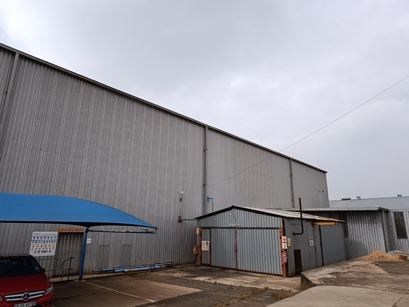 Large industrial warehouse and office building of Currie Group with metal siding and loading area, under a cloudy sky.