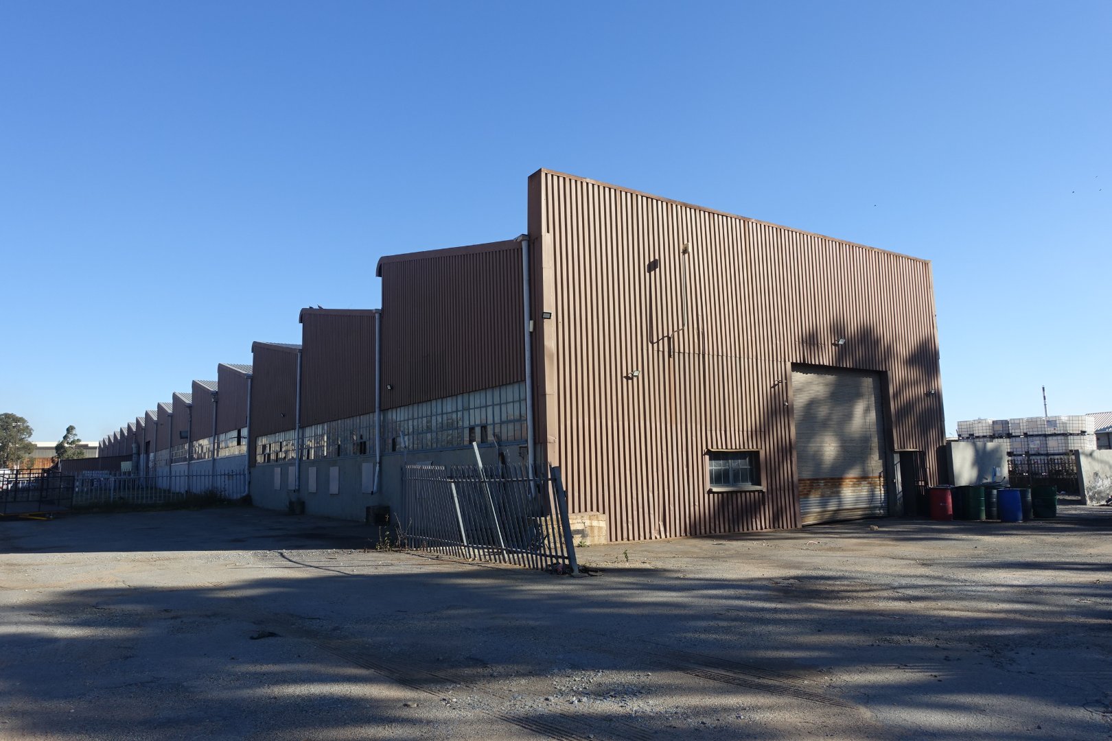 Large industrial warehouse building with metal siding and a clear blue sky, part of Currie Group's facilities since 1887.
