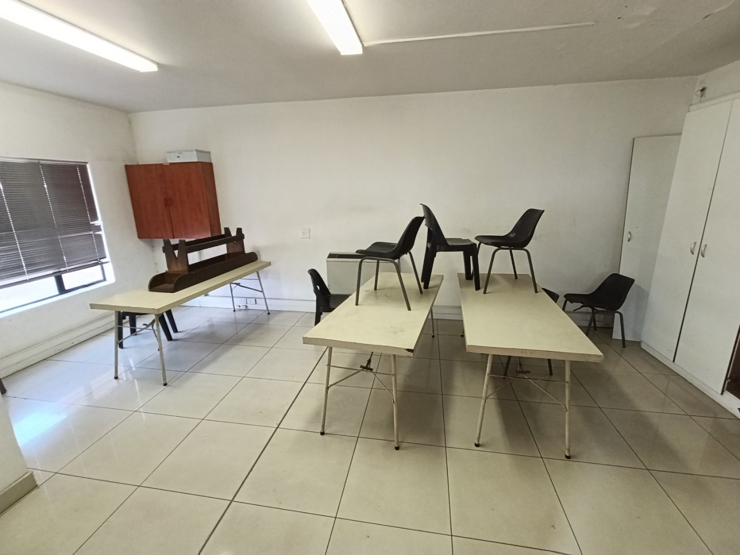 Currie Group Warehouse Interior Spacious warehouse interior with tables and chairs, used for meetings or training sessions, featuring white walls and tiled flooring.