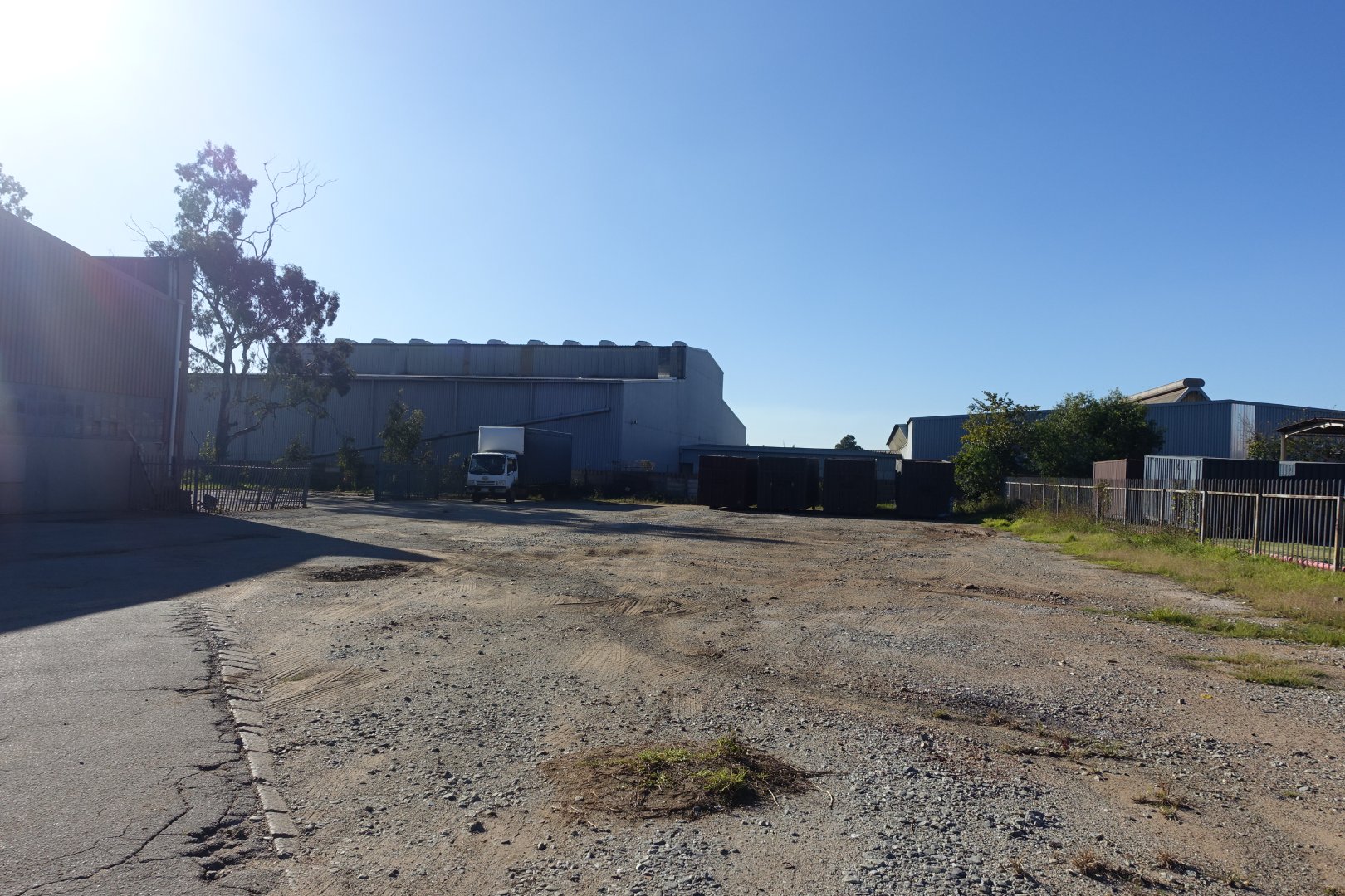 Currie Group Offices and Warehouses Exterior view of Currie Group offices and warehouses with open lot and clear blue sky, showcasing industrial facilities since 1887.