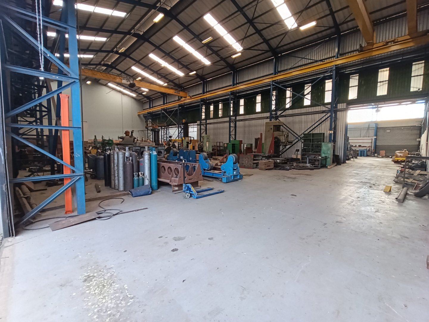 Currie Group Warehouse Interior Spacious industrial warehouse with high ceilings, metal racks, and manufacturing equipment, showcasing Currie Group's facilities since 1887.
