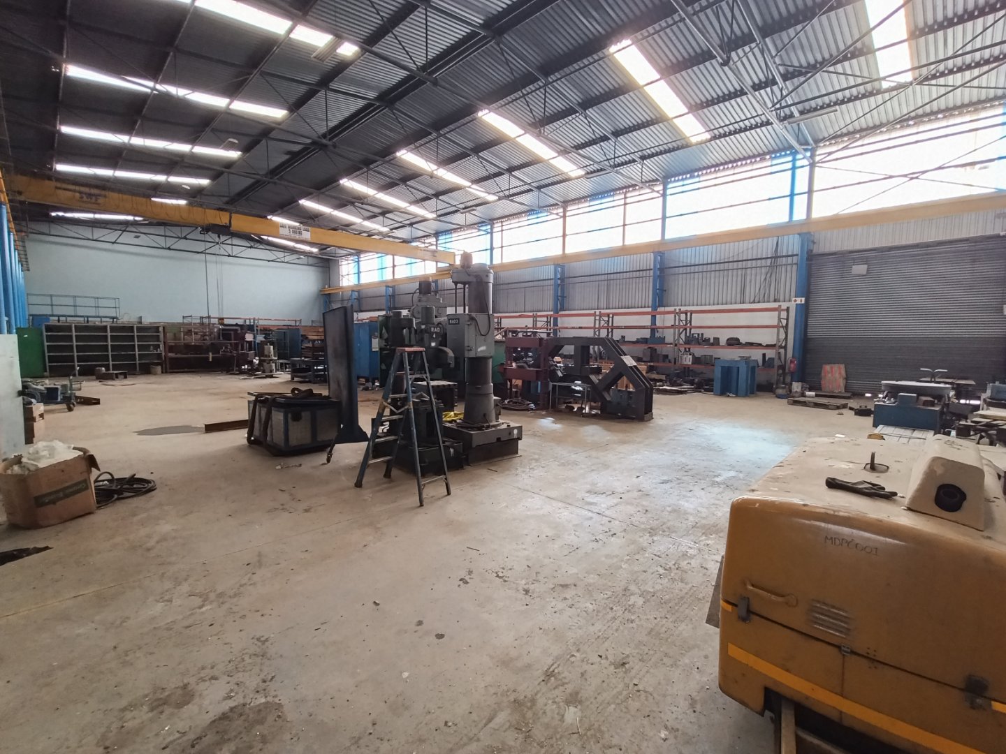 Spacious industrial warehouse interior Large industrial warehouse with high ceilings, metal beams, and machinery, showcasing a clean and organized workspace for manufacturing or storage.