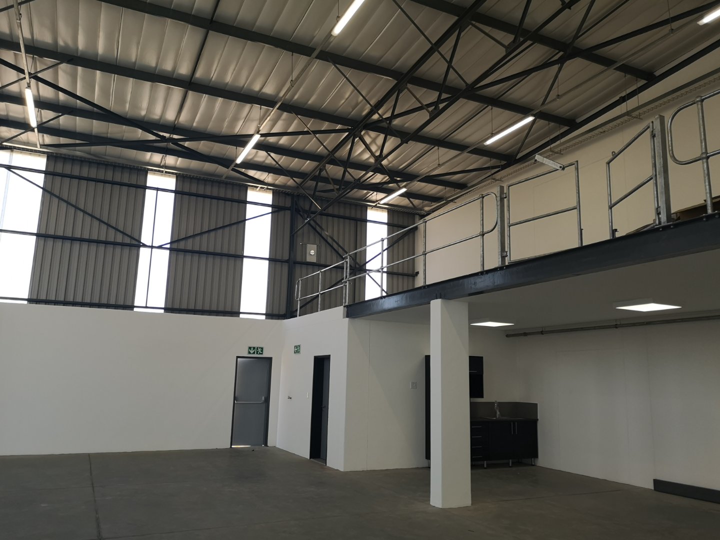 Modern Warehouse Interior at Currie Group Spacious warehouse interior with high ceilings, metal roofing, and a mezzanine level, showcasing Currie Group's modern office and storage facilities.