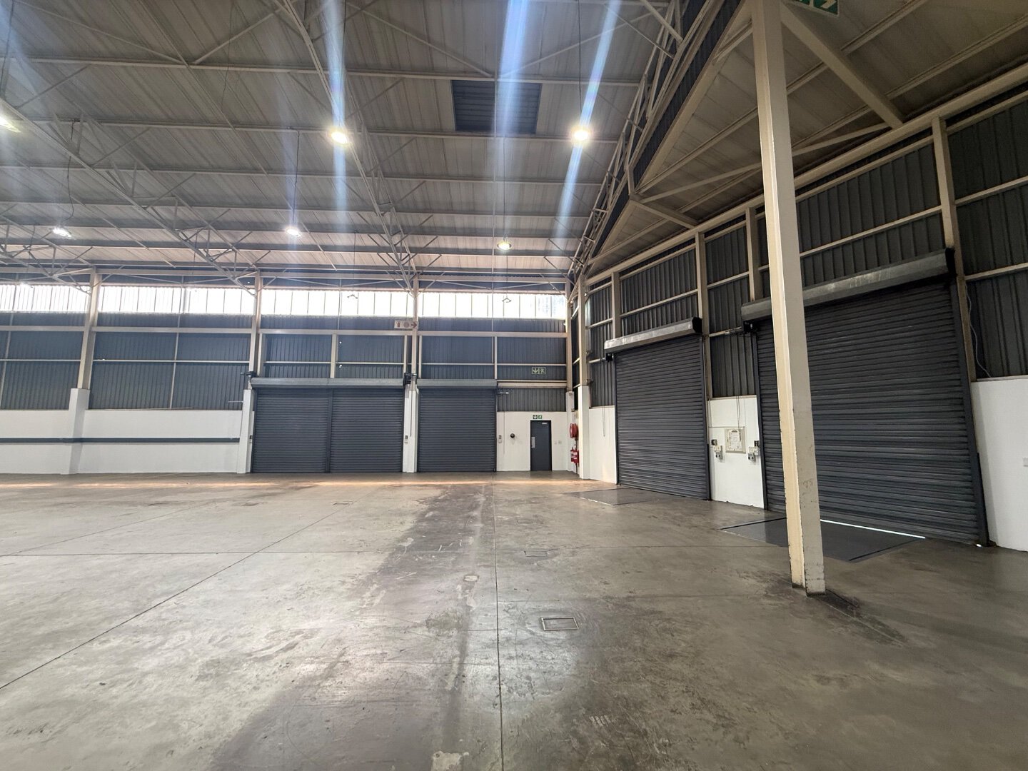 Modern Commercial Warehouse Interior Spacious commercial warehouse with high ceilings, roller shutter doors, and polished concrete floors, suitable for storage and logistics in Bryanston.