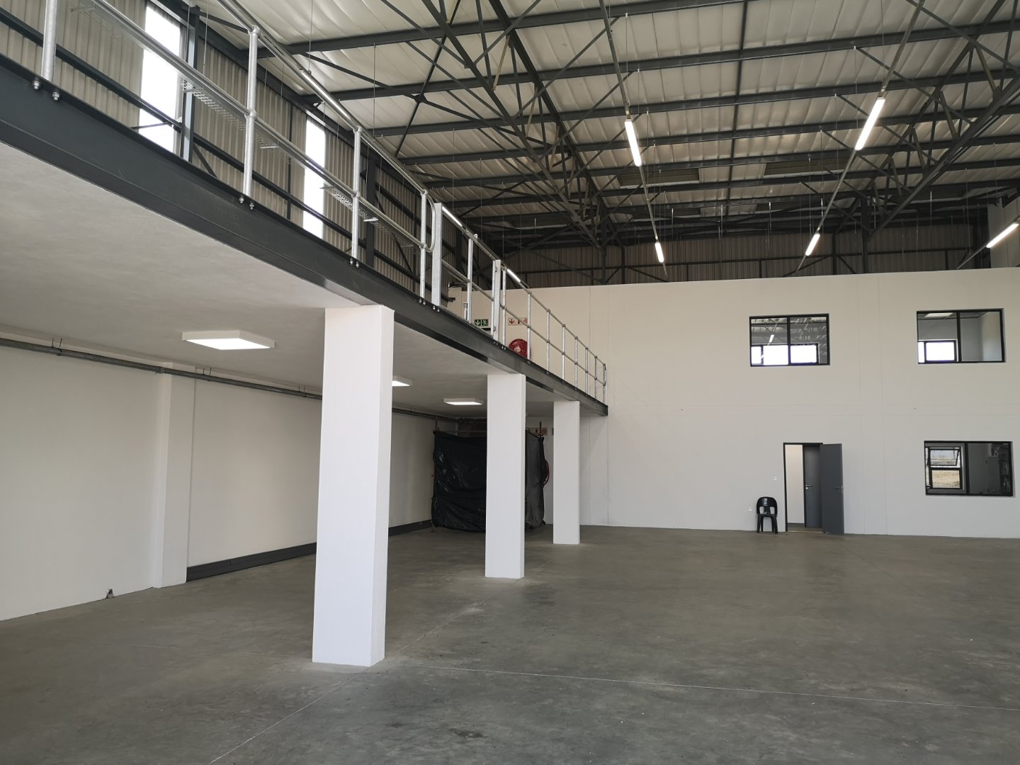 Modern Office & Warehouse Space Spacious modern office and warehouse interior with high ceilings, mezzanine level, and large open area for versatile use.