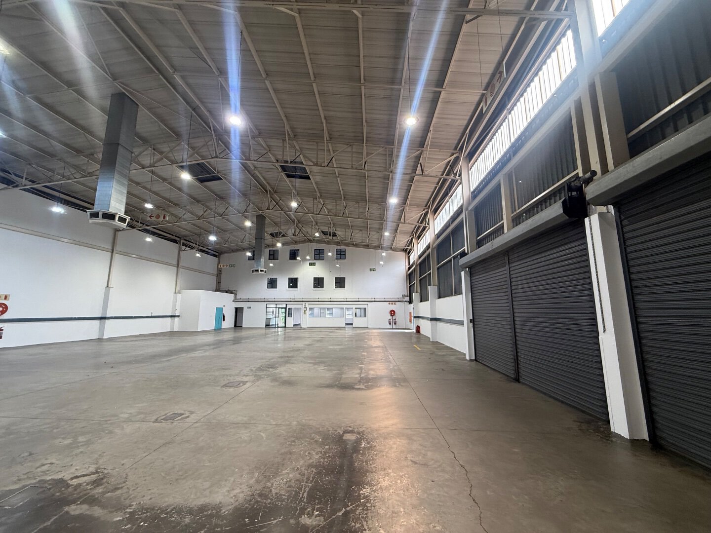 Spacious Commercial Warehouse Interior Interior view of a large, modern commercial warehouse with high ceilings, ample lighting, and roller shutter doors, suitable for storage and logistics in Bryanston.