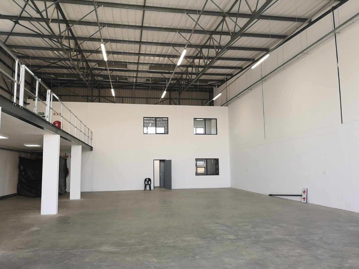 Currie Group Warehouse Interior Spacious warehouse interior with high ceilings, white walls, and concrete flooring, showcasing modern industrial office and storage space.