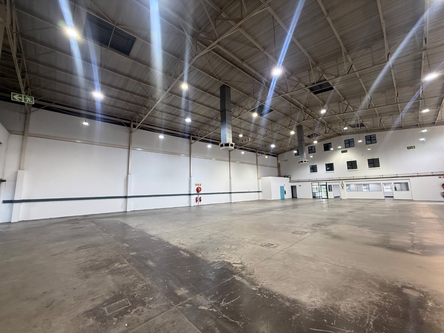 Spacious Commercial Warehouse Interior Interior view of a large, modern commercial warehouse with high ceilings, bright lighting, and polished concrete floors, suitable for storage and logistics.