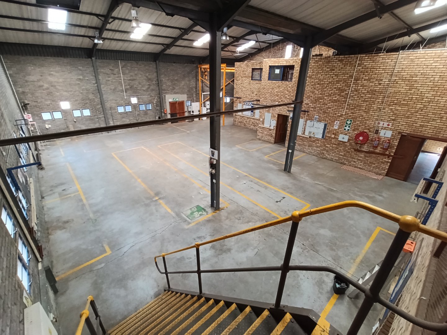 Spacious Office Warehouse at Currie Group Interior view of a large, open office warehouse space with high ceilings, brick walls, and designated parking spots, showcasing modern industrial design.
