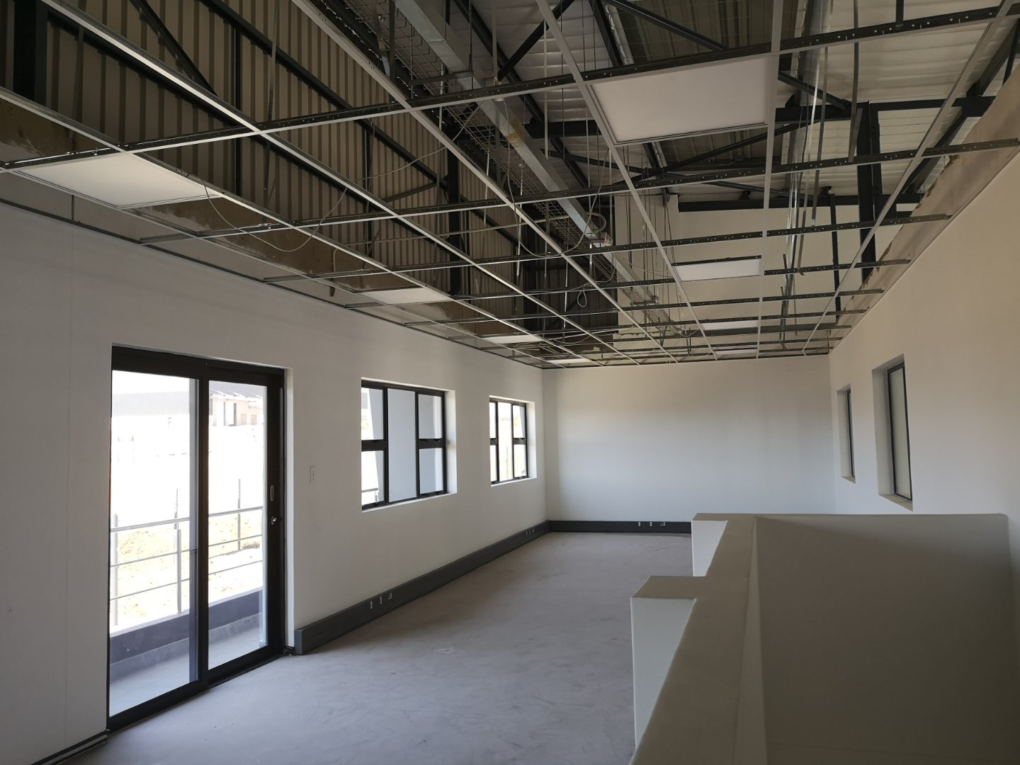 Currie Group Office Interior Construction Modern office space under construction with exposed ceiling framework, large windows, and white walls, part of Currie Group's office and warehouse facilities.