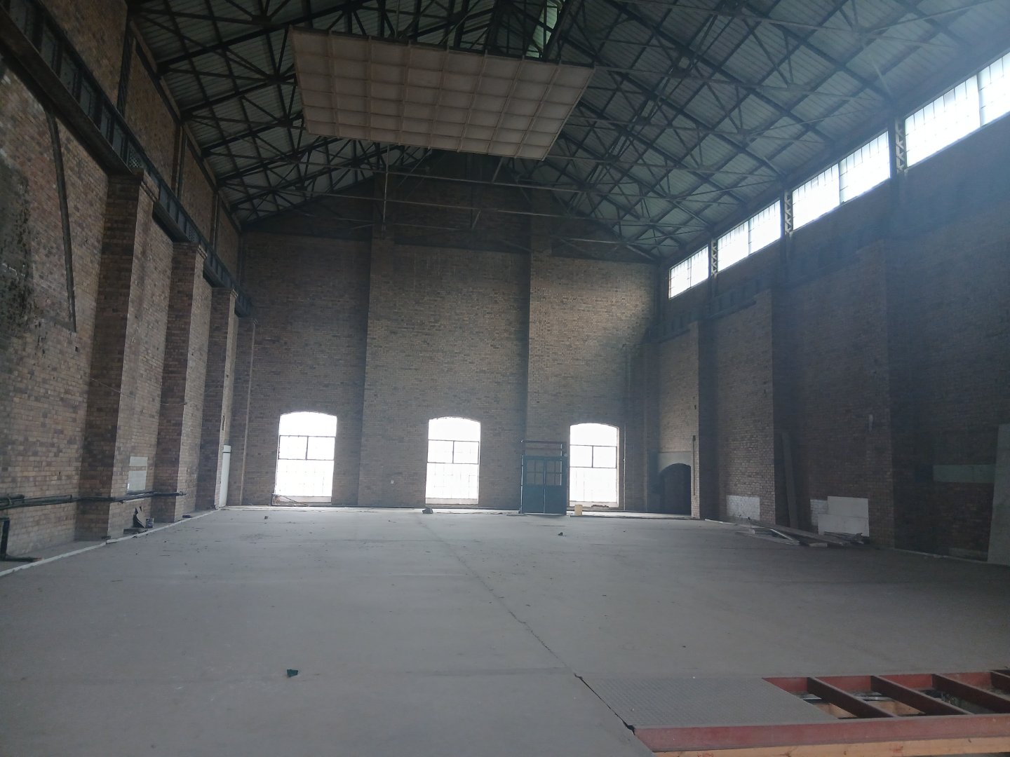 Currie Group Offices and Warehouses Spacious industrial warehouse interior with high ceilings, brick walls, and large windows providing natural light, suitable for storage and manufacturing.