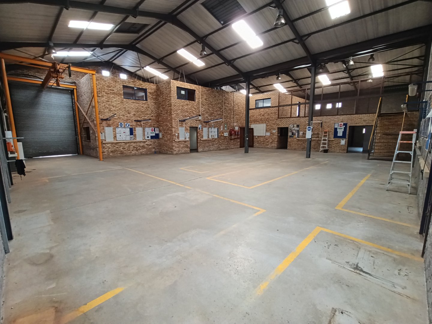 Currie Group Offices & Warehouses Interior Spacious interior of Currie Group offices and warehouses with high ceilings, brick walls, and designated parking areas.
