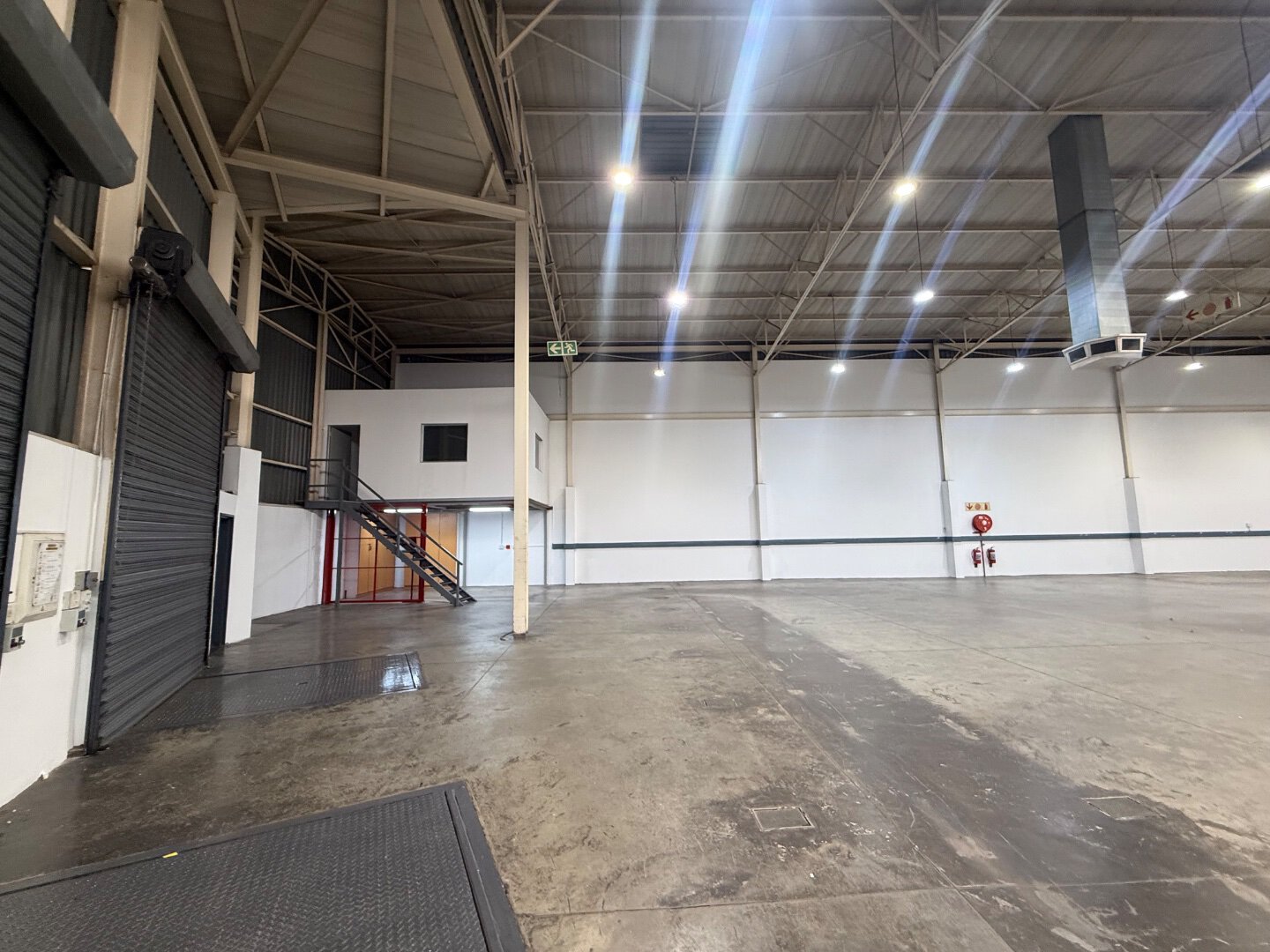 Spacious Commercial Warehouse Interior Interior view of a large, empty commercial warehouse with high ceilings, bright lighting, and concrete flooring, suitable for storage or distribution.