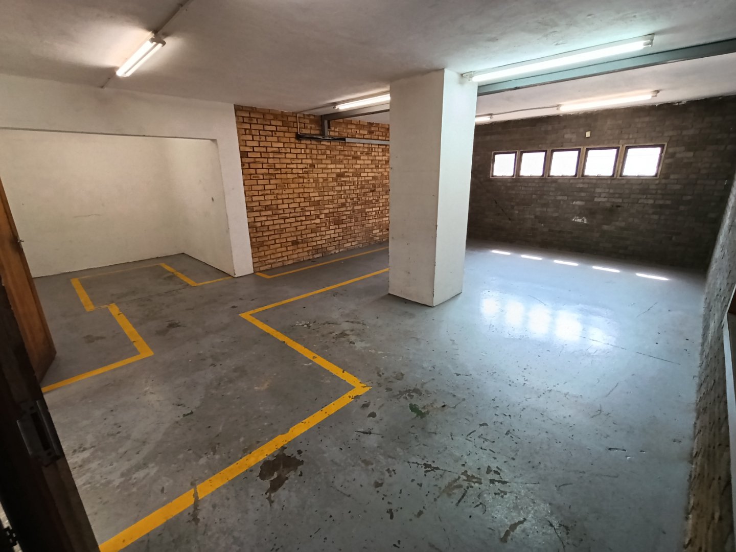 Office Parking Area at Currie Group Underground office parking space with marked parking spots and brick wall, part of Currie Group's office facilities since 1887.