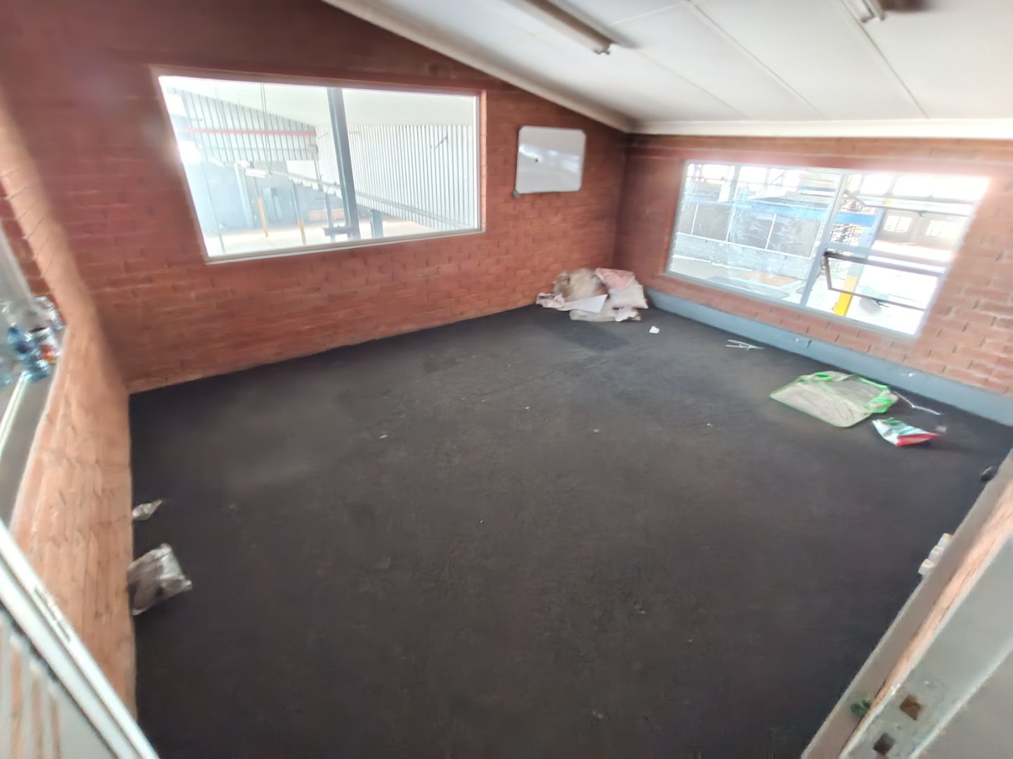 Industrial Office Space in Alrode Spacious industrial office interior with large windows, brick walls, and a black carpeted floor, part of Currie Group's office facilities in Alrode.