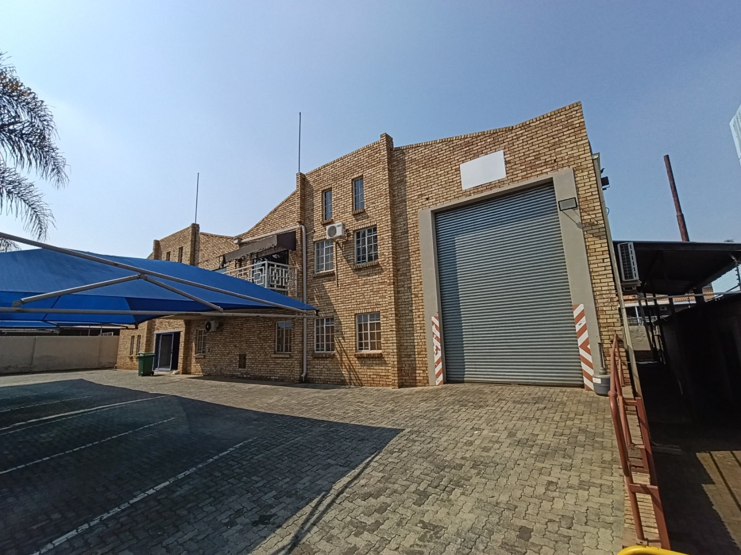 Exterior view of Currie Group offices and warehouses with brick facade, large roller shutter door, and parking area under a clear blue sky.
