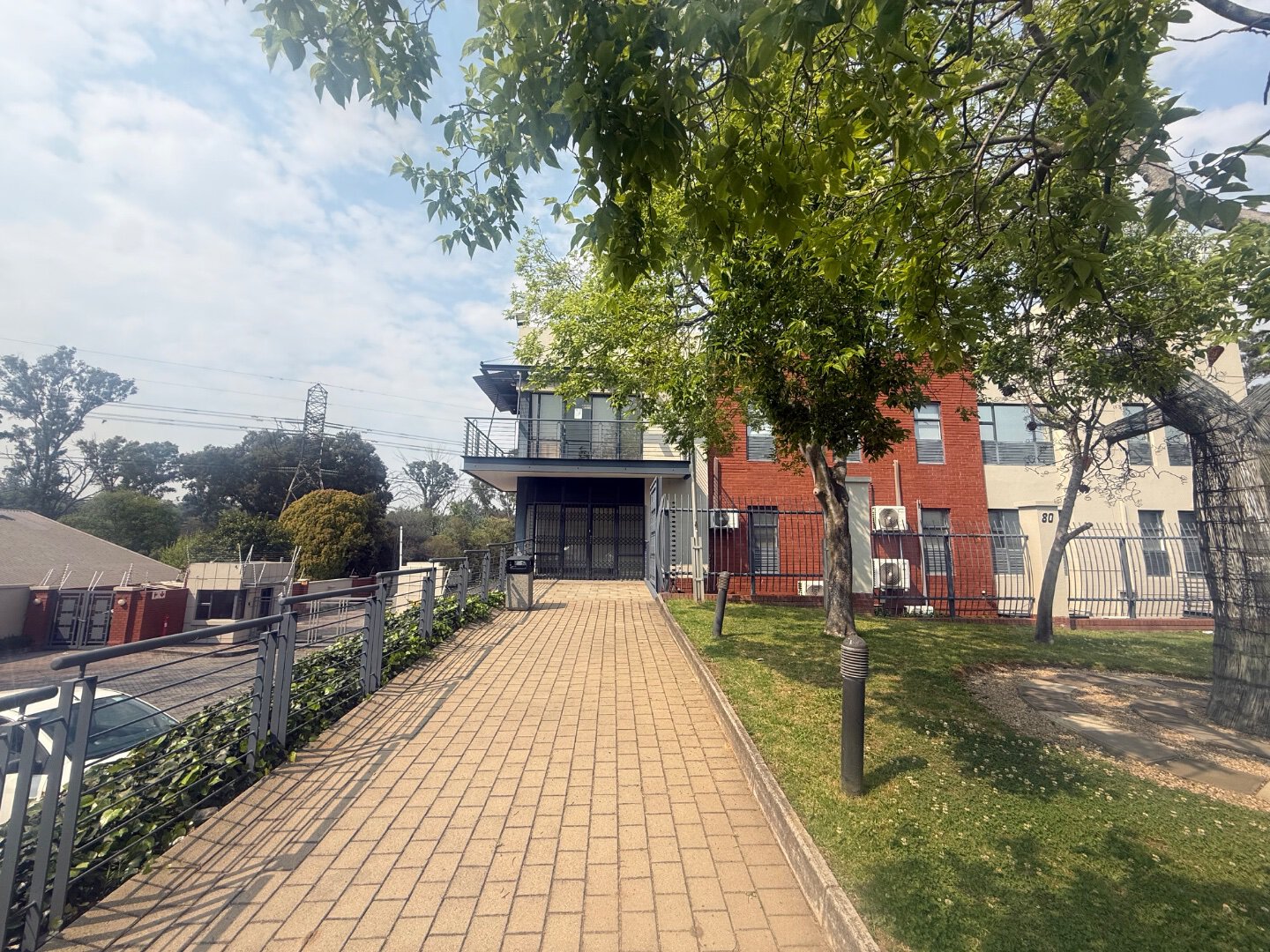 Modern commercial property with office and warehouse space in Bryanston, surrounded by greenery and accessible via a paved walkway.