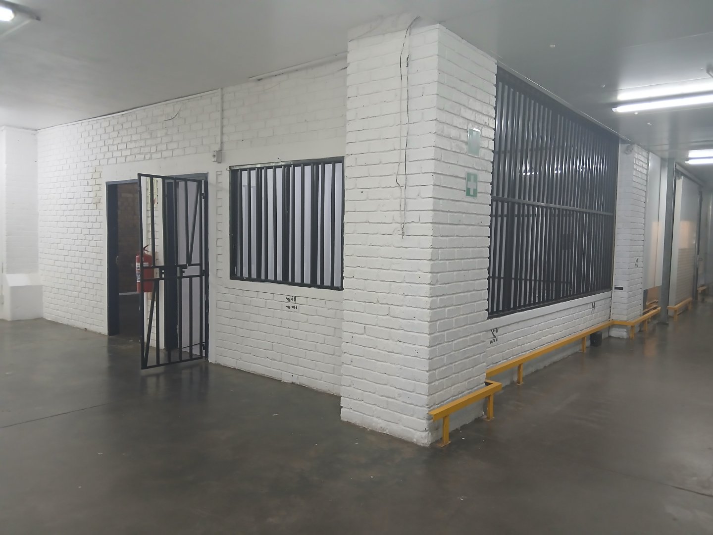 Interior view of Currie Group offices and warehouses with white brick walls, black metal window frames, and yellow safety benches in a modern industrial facility.