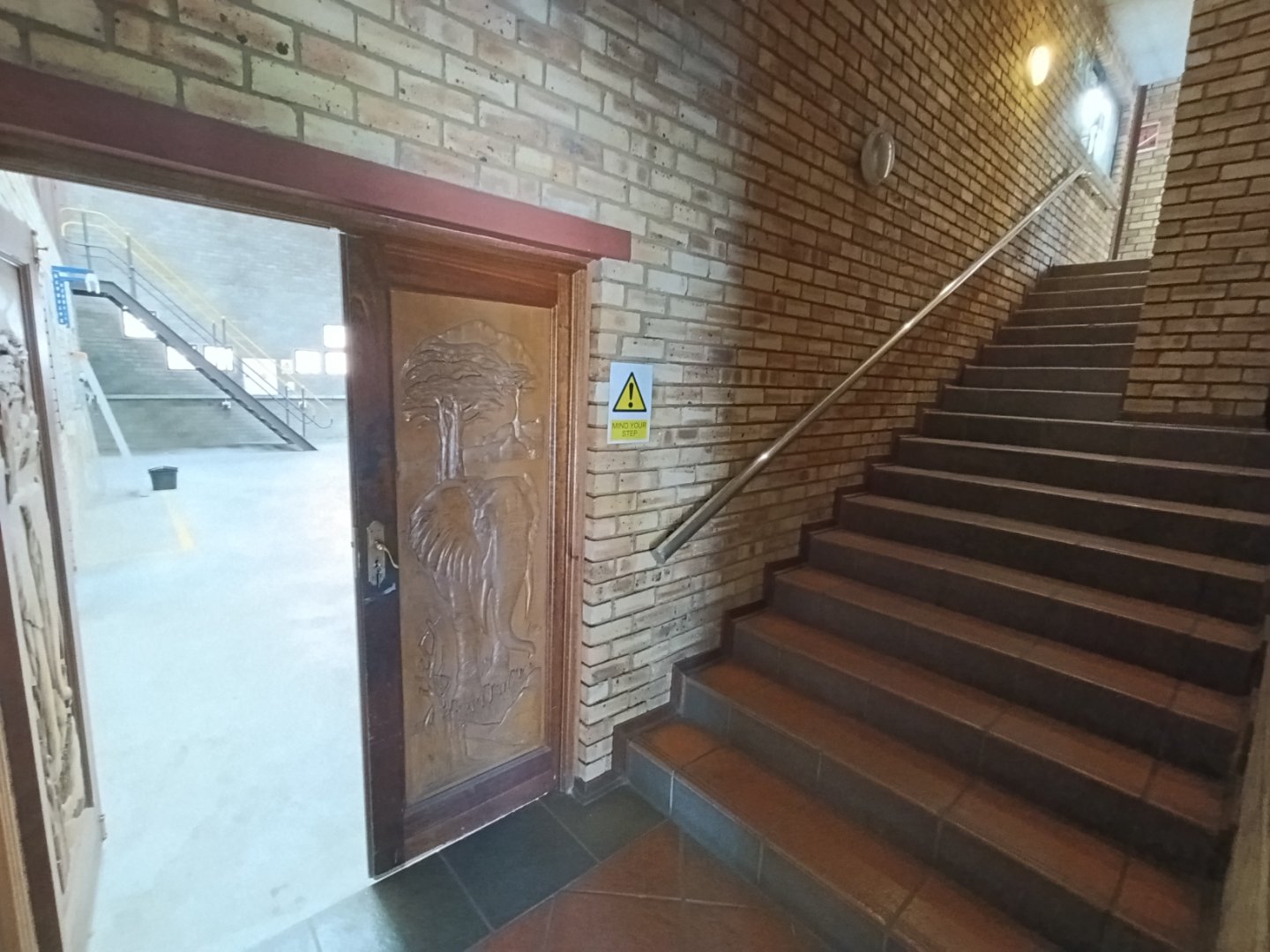 Currie Group Office Entrance and Stairs Interior view of Currie Group office entrance with stairs and brick walls, showcasing industrial design and safety signage.