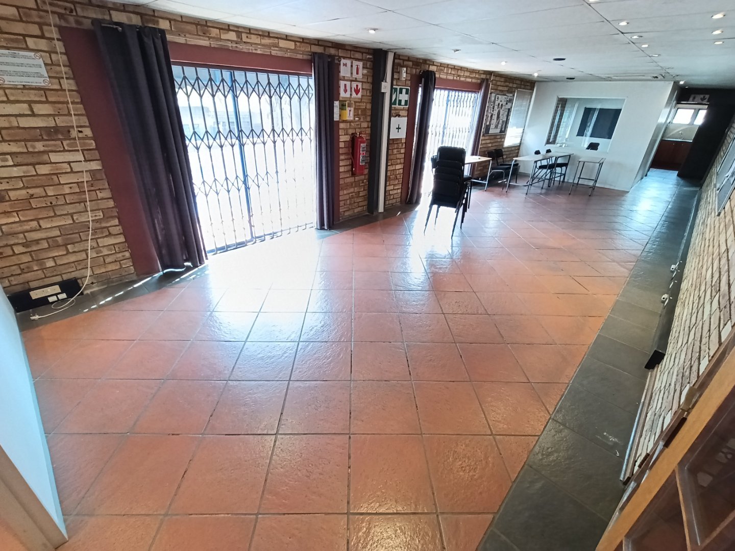 Currie Group Offices and Warehouses Spacious interior of Currie Group offices and warehouses with brick walls, tiled floors, and large windows with security bars.