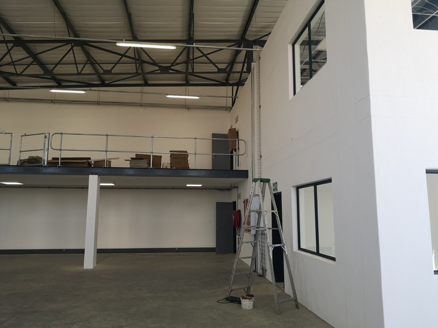 Currie Group Offices & Warehouses Interior Modern industrial office and warehouse interior with high ceilings, large windows, and a mezzanine level under construction.