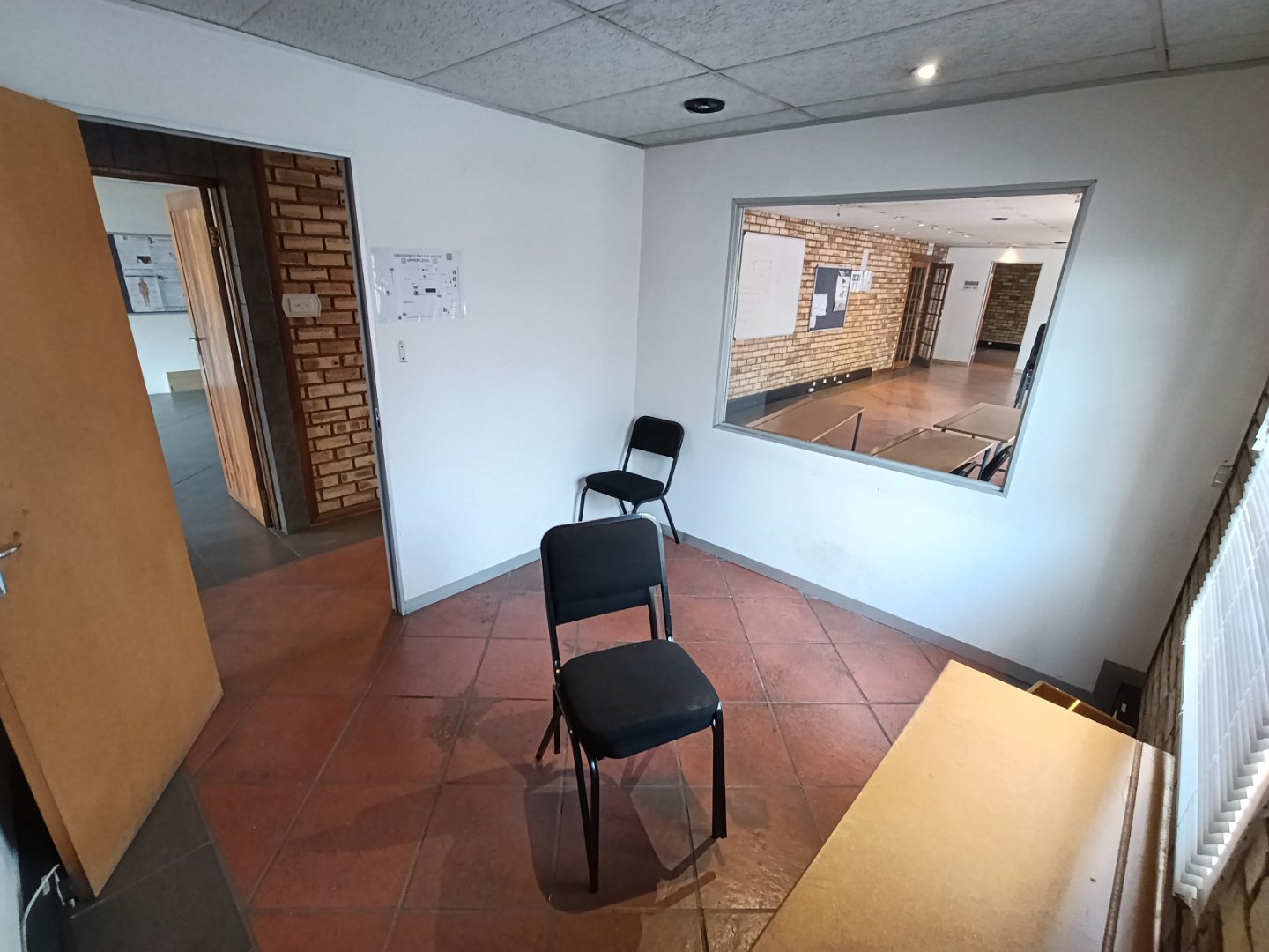 Office Meeting Room at Currie Group Empty office meeting room with two chairs, a window, and a view into a larger space at Currie Group offices.